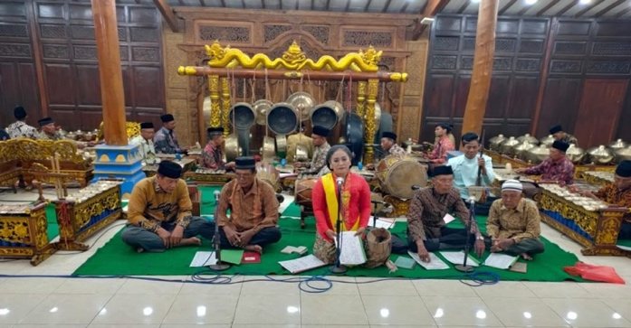 Pengrawit dan pesinden duduk bersila di pendopo lengkap dengan gamelan saat pentas berlangsung.